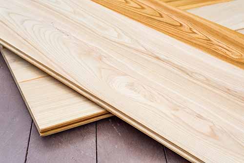 Ash boards showing contrast between raw and finished Ash wood flooring boards partially raw and partially varnished